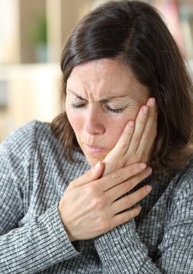 woman holding her jaw in pain